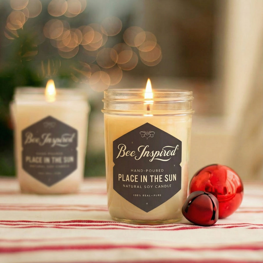 Two lit candles labeled 'Bee Inspired' on a table with a blurred background