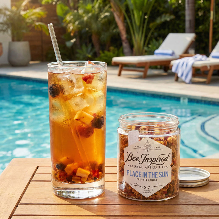 Glass of place in the sun iced tea with a jar of 'Bee Inspired' tea on a poolside table