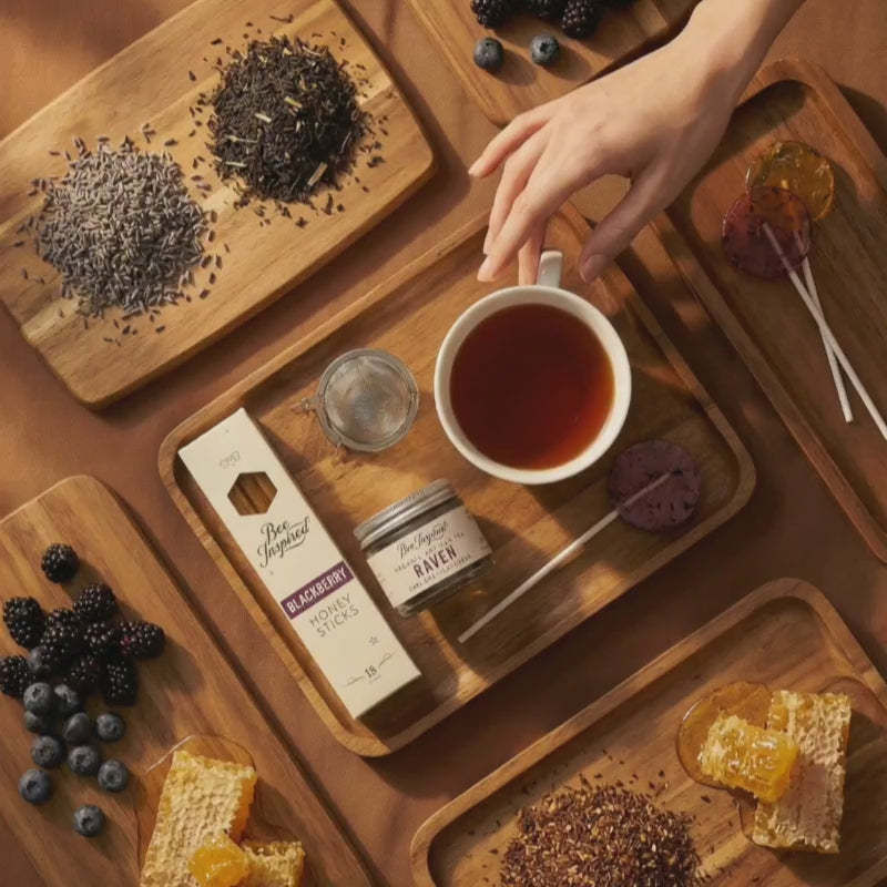 Hand picking up a cup of tea surrounded by products from the Tea and Honey Gift Set.