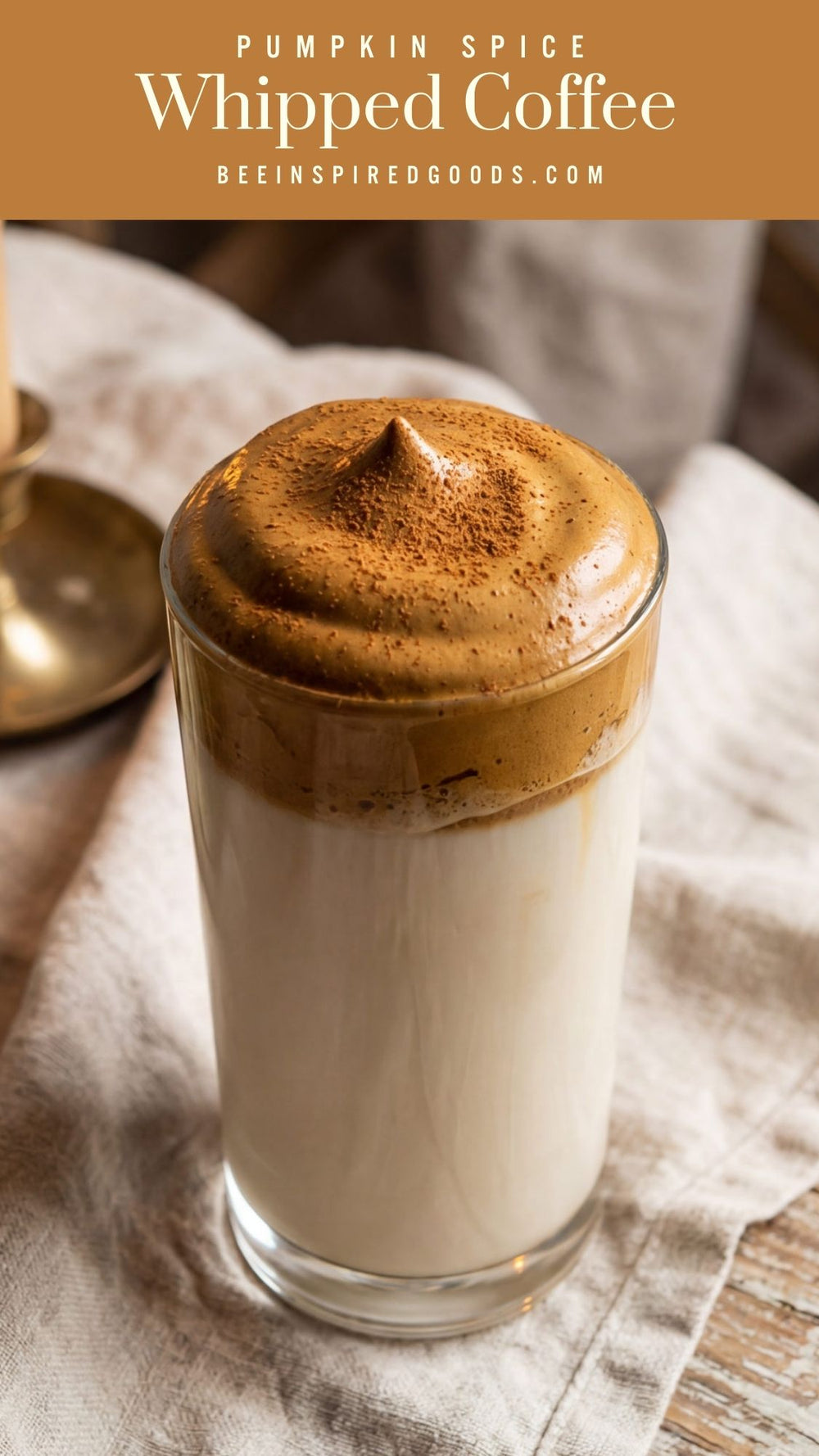 Pumpkin spice whipped coffee in a glass on top of milk.