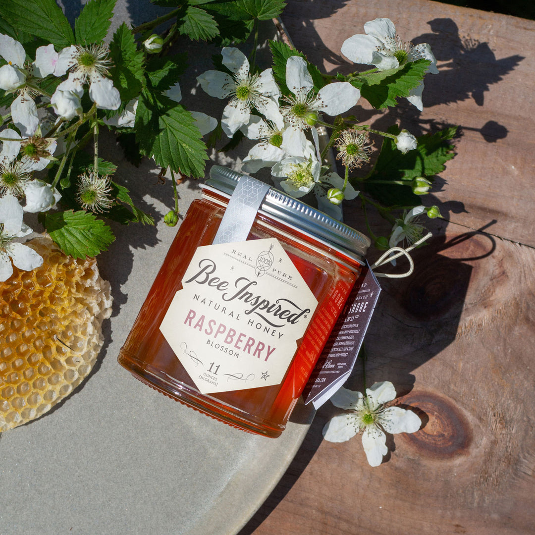 Raspberry honey flat lay with raspberry blooms and honeycomb on outdoor table 