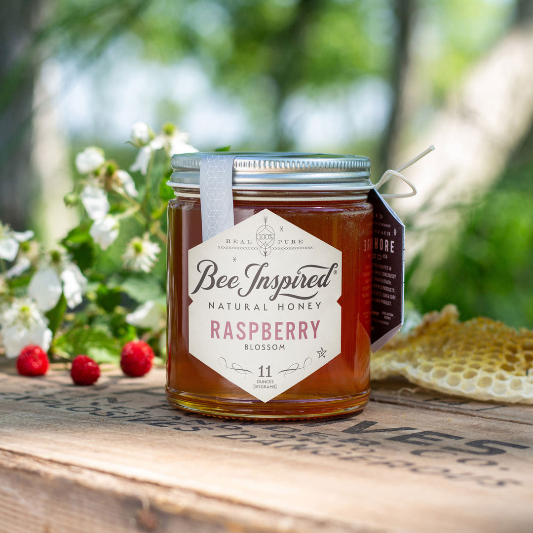 Raspberry honey, raspberry blooms, and honeycomb on outdoor table 