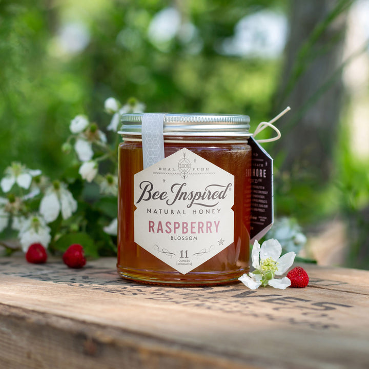 Raspberry honey on outdoor table with raspberry blooms 