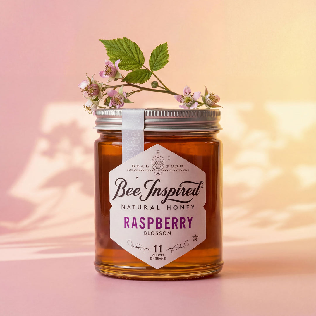 Jar of 'Bee Inspired' natural honey with raspberry blossom on a soft pink background