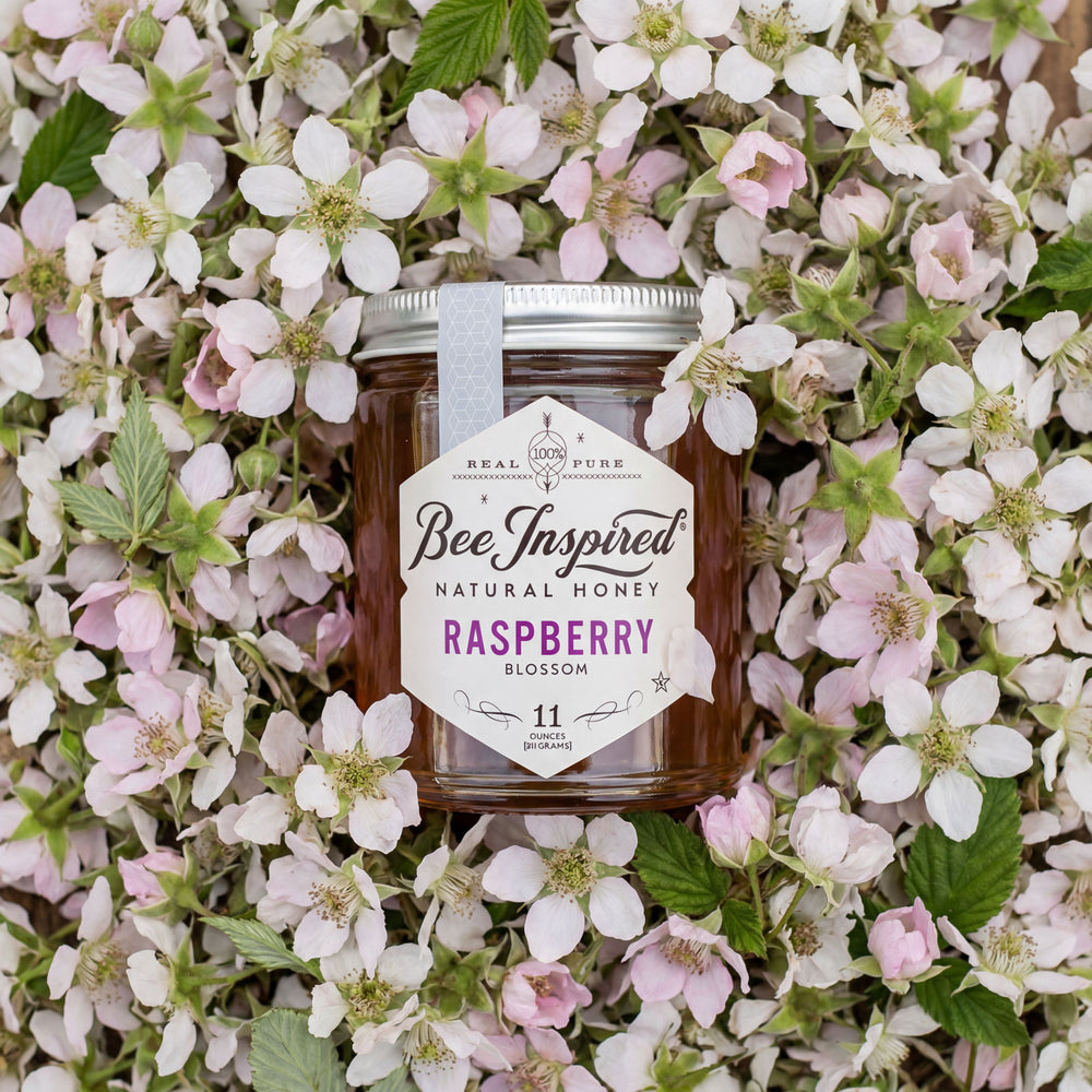 Jar of BeeInspired natural honey surrounded by flowers