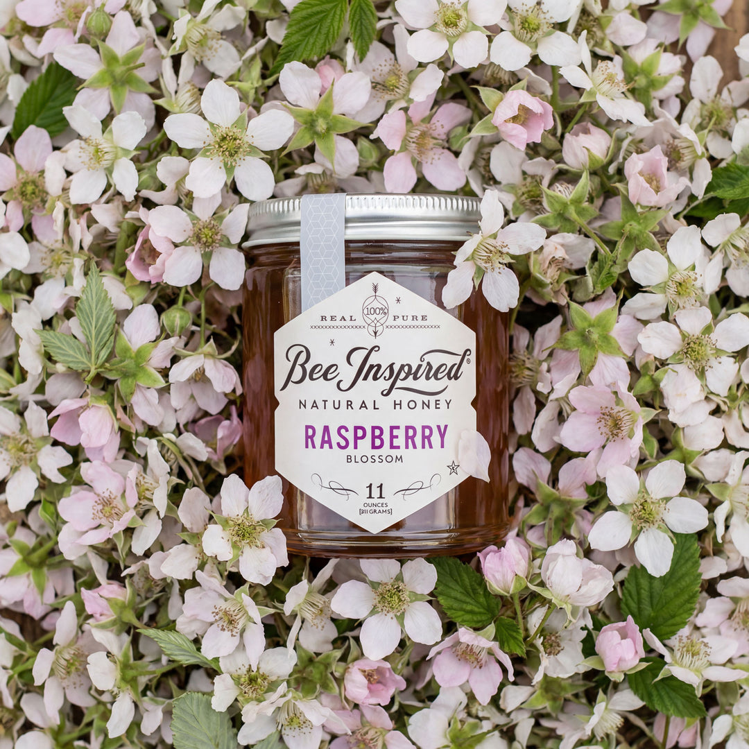 Jar of BeeInspired natural honey surrounded by flowers