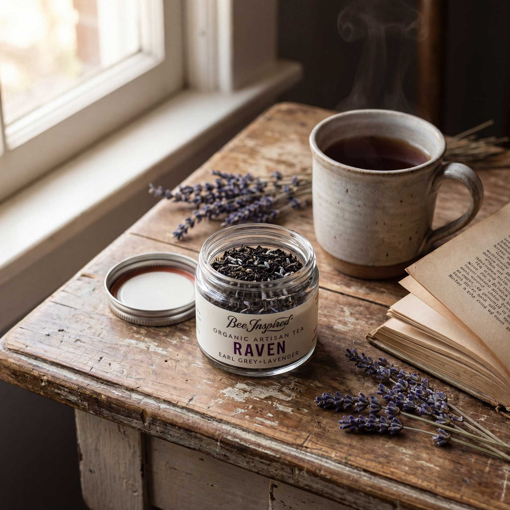 Jar of 'Raven' tea, cup of tea, and lavender on a wooden table near a window.