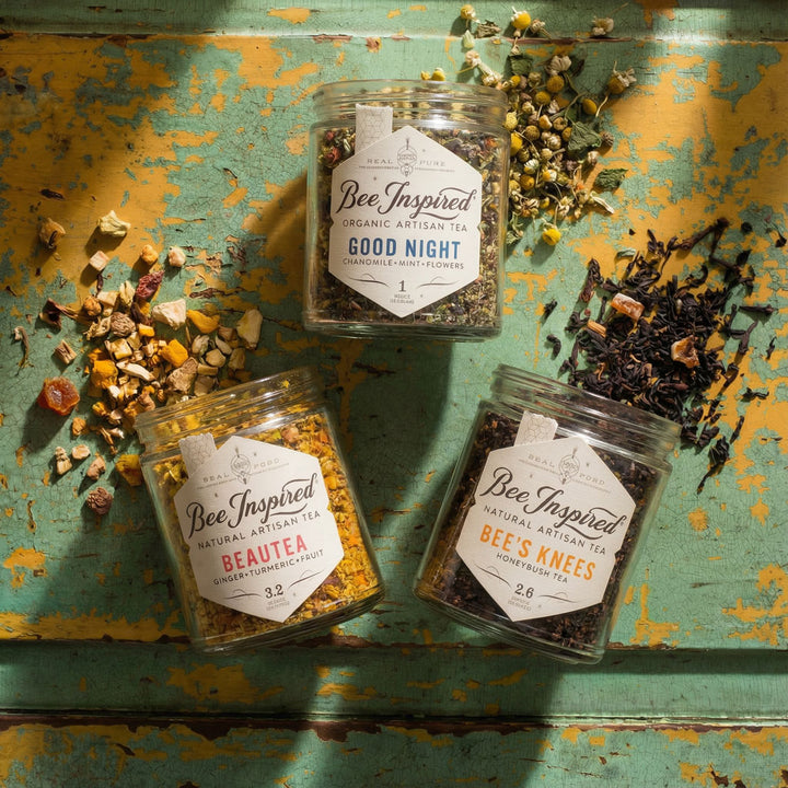 Relaxation Gift Set of 3 jars of 'Bee Inspired' tea on a rustic painted wooden surface with loose leaf tea