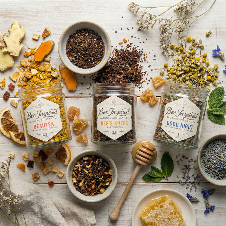 Assorted herbal teas and ingredients on a wooden surface with 'Bee Inspired' branding.
