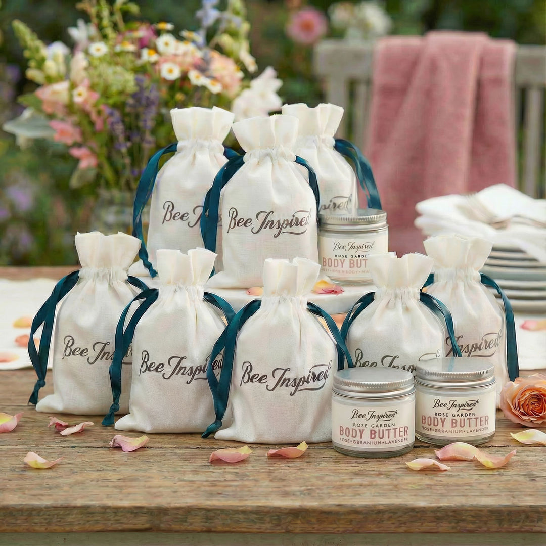 Bee Inspired body butter party favors ars with drawstring bags on a wooden table outdoors.