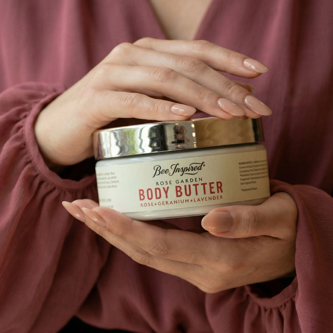 Person holding a jar of Bee Inspired Body Butter with a soft pink background