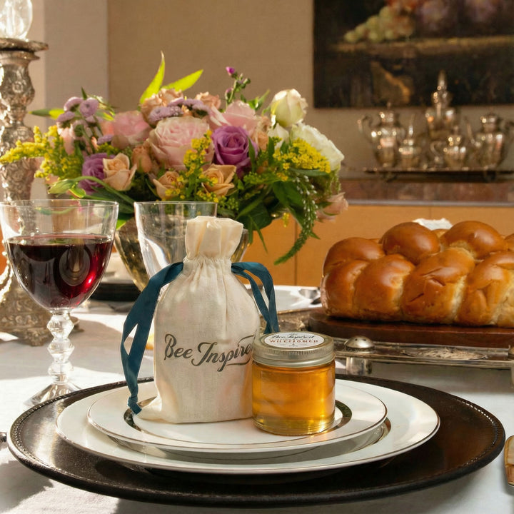 Rosh Hashanah table setting with a bottle labeled 'Bee Inspired', honey party favors and challah on a table.