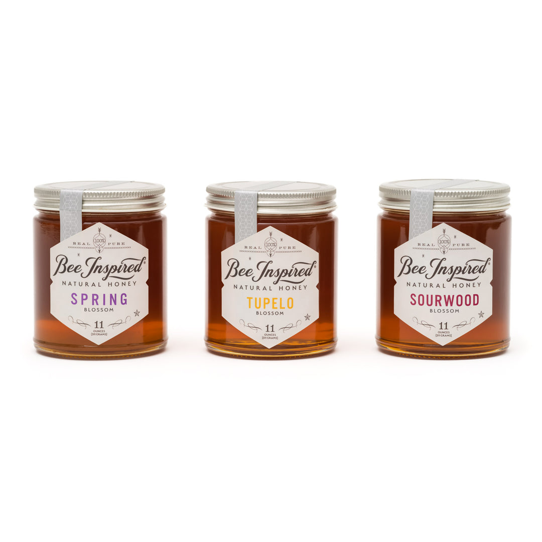 Three jars of 'Bee Inspired' honey with different flavors on a white background