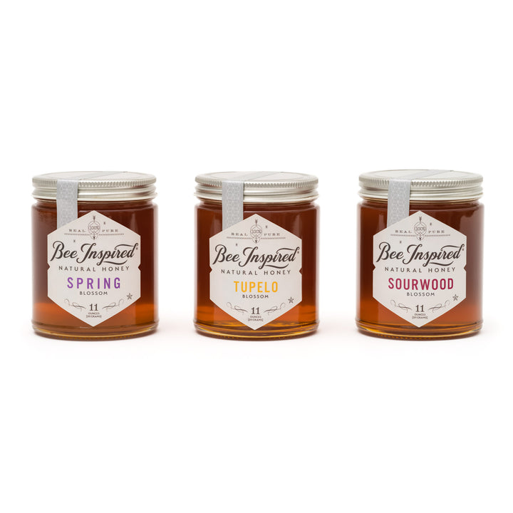Three jars of 'Bee Inspired' honey with different flavors on a white background