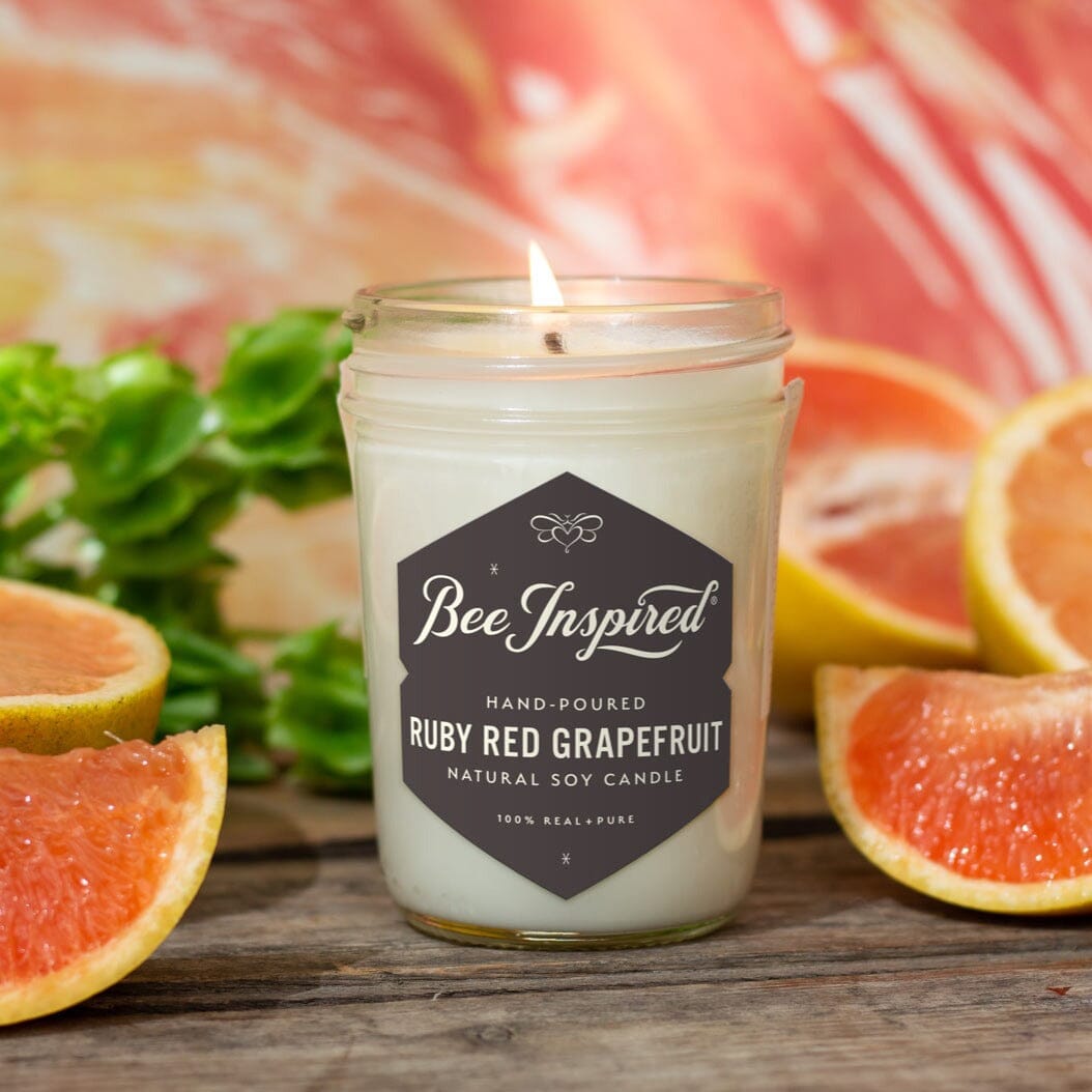 Ruby Red Grapefruit Jelly Jar Candle surrounded by art and fruit