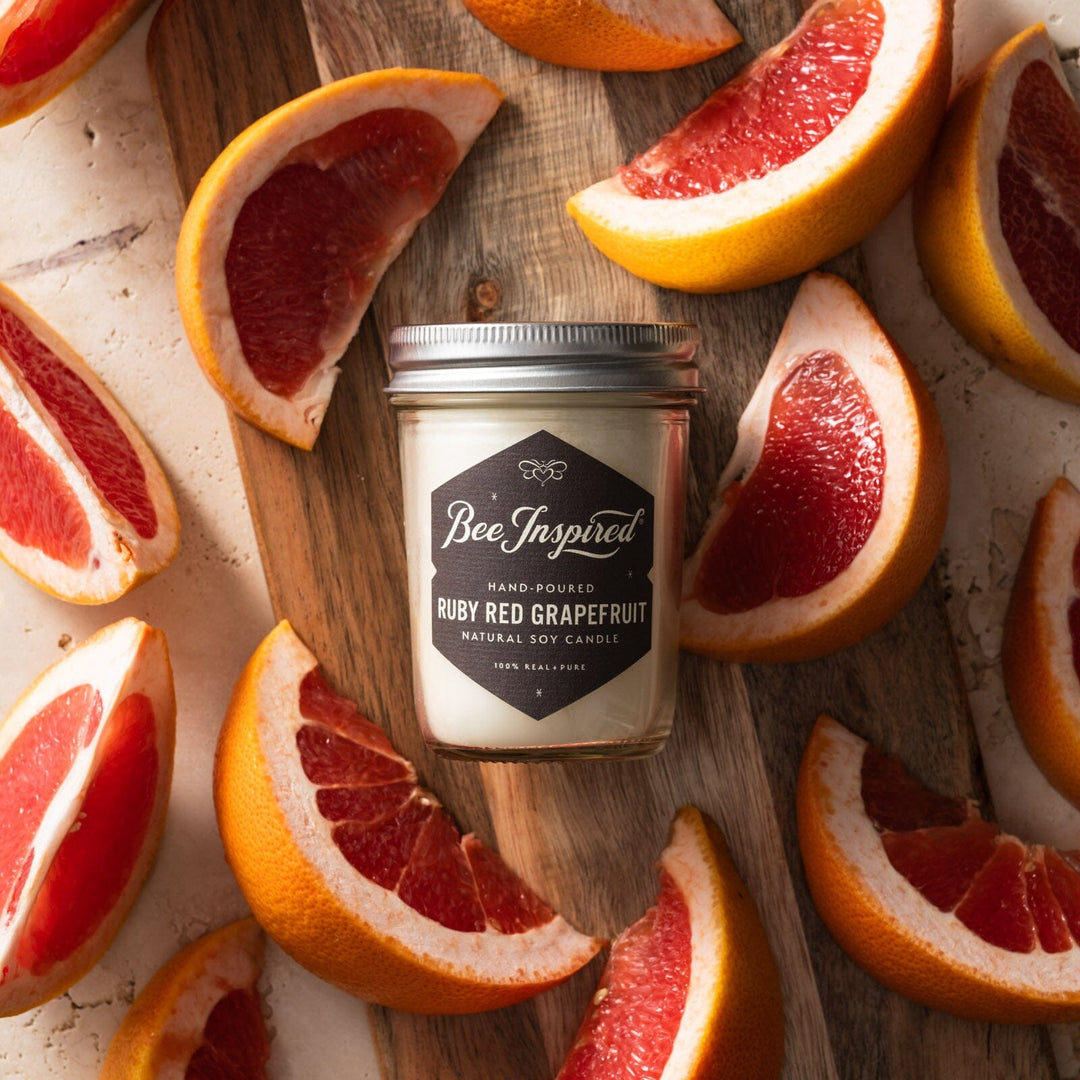 Ruby Red Grapefruit Jelly Jar Candle surrounded by grapefruit on a cutting board