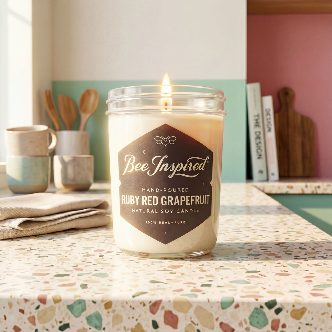 Candle jar labeled 'Bee Inspired' with 'Ruby Red Grapefruit' scent on a terazzo kitchen counter