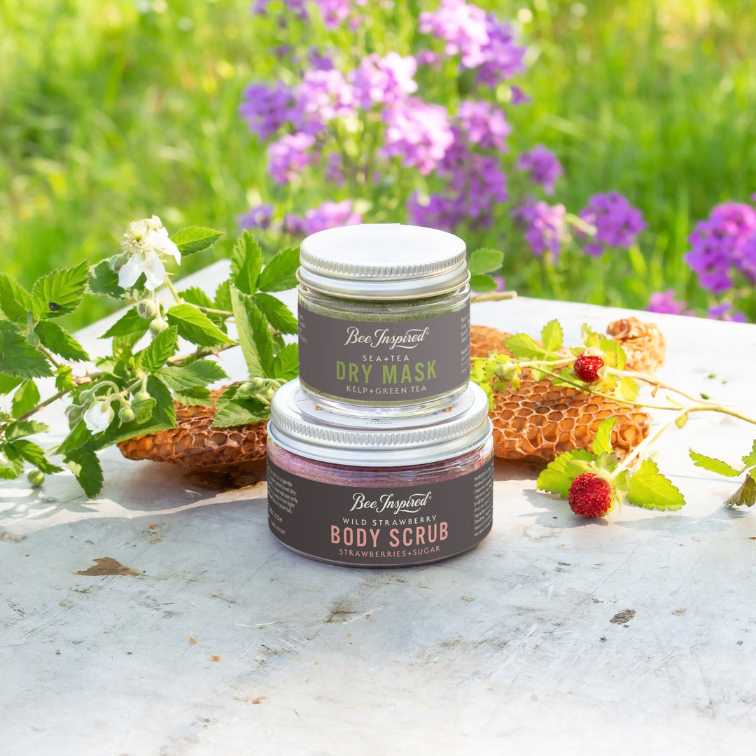 Sea+Tea dry mask and Wild Strawberry body scrub in front of flowers and honeycomb 