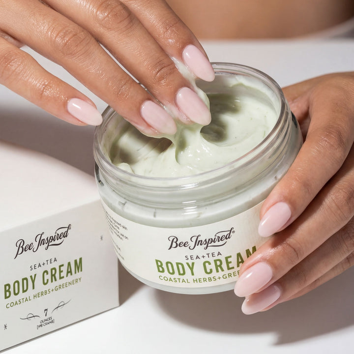 Hand holding a jar of 'Bee Inspired' body cream with visible branding.
