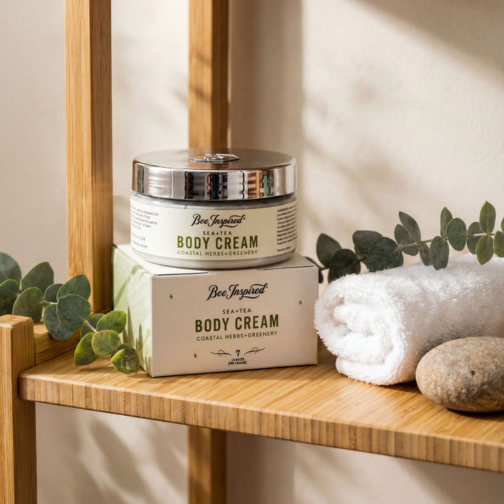 Body cream jar and packaging on a wooden shelf with eucalyptus leaves and a towel.