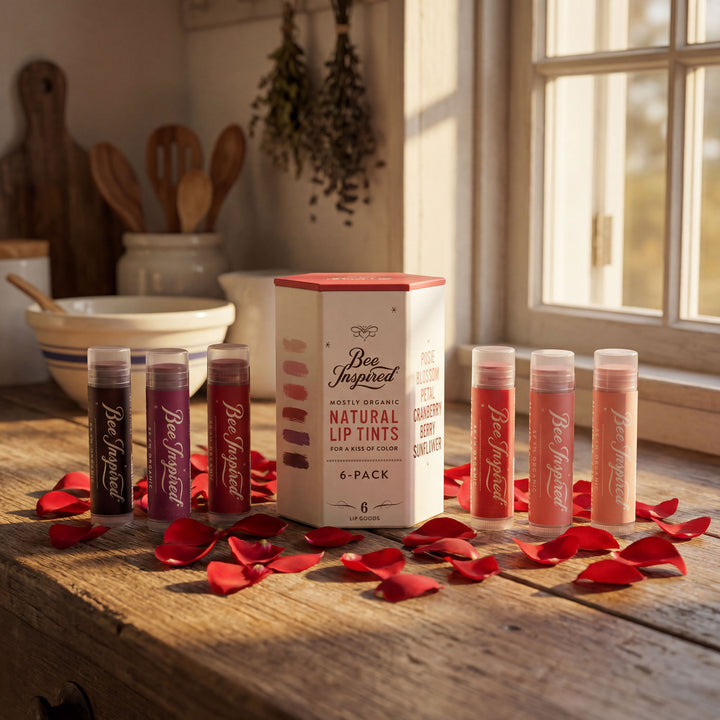 Set of lip tint tubes with a box on a wooden surface with red petals.