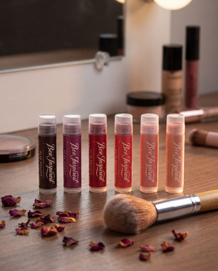 Set of lip balms with visible branding on a wooden surface with makeup tools.