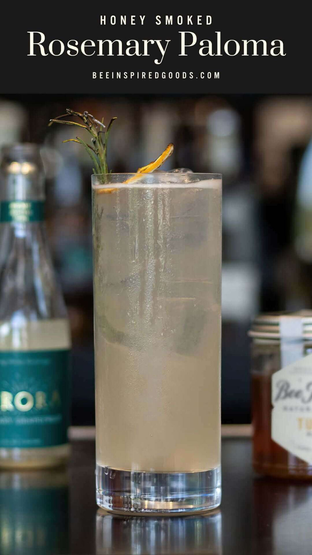 "Honey Smoked Rosemary Paloma beeinspiredgoods.com" with a glass of paloma topped with a dried orange slice 