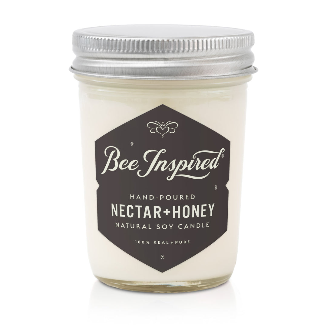 Candle jar labeled 'Bee Inspired Nectar + Honey' on a white background