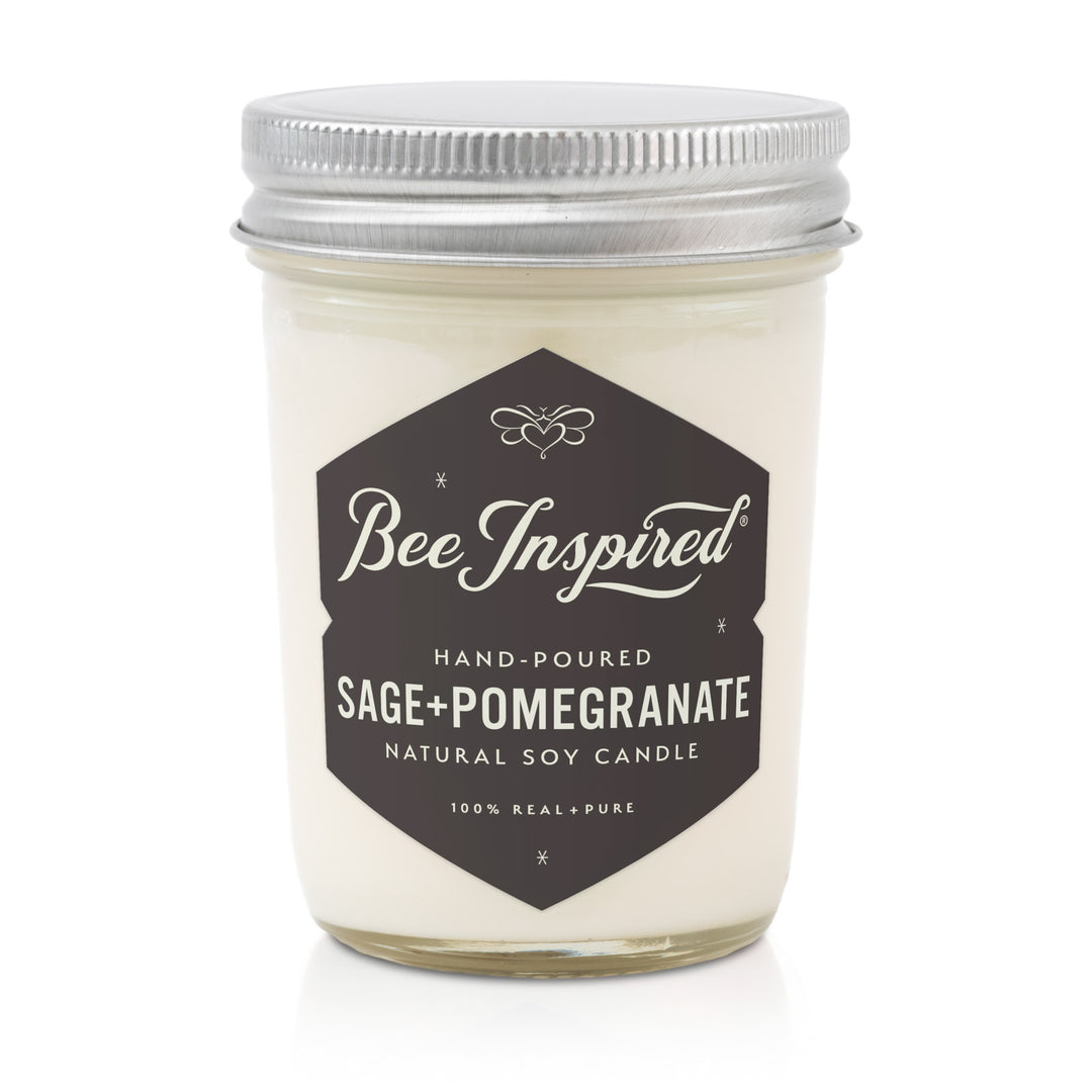 Candle jar labeled 'Bee Inspired' with 'Sage + Pomegranate' scent on a white background