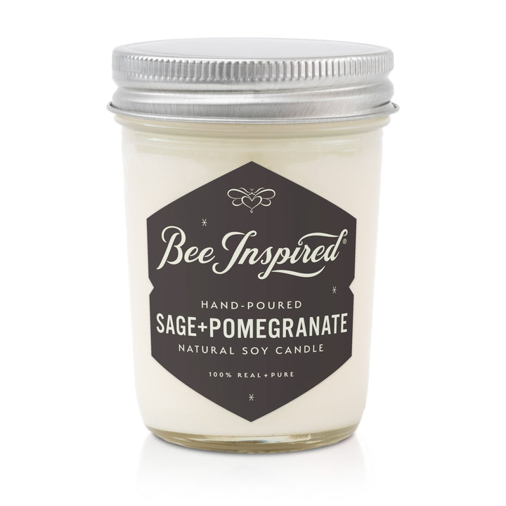 Candle jar labeled 'Bee Inspired' with 'Sage + Pomegranate' scent on a white background