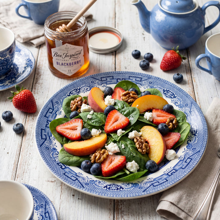 Salad with strawberries, blueberries, and peaches on a decorative plate with a teapot and cups in the background.