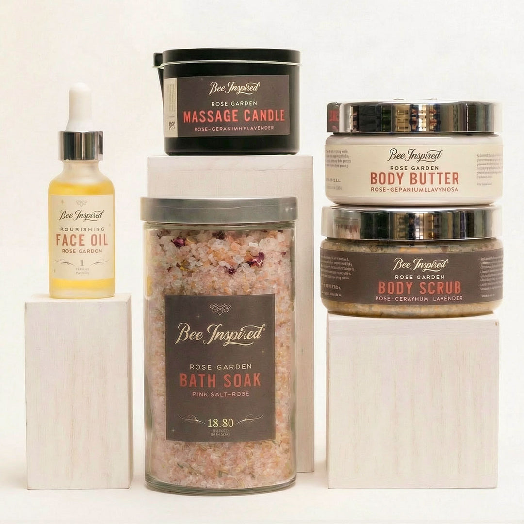 Collection of Bee Inspired beauty products including a face oil, massage candle, bath soak, body butter, and body scrub on a white background.