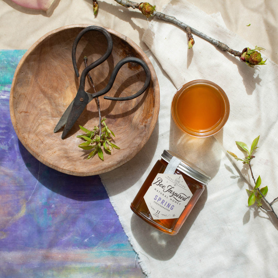 Spring honey next to wooden bowl and purple art 