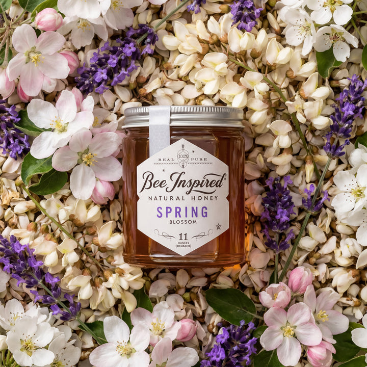 Jar of 'Bee Inspired' natural honey surrounded by spring flowers