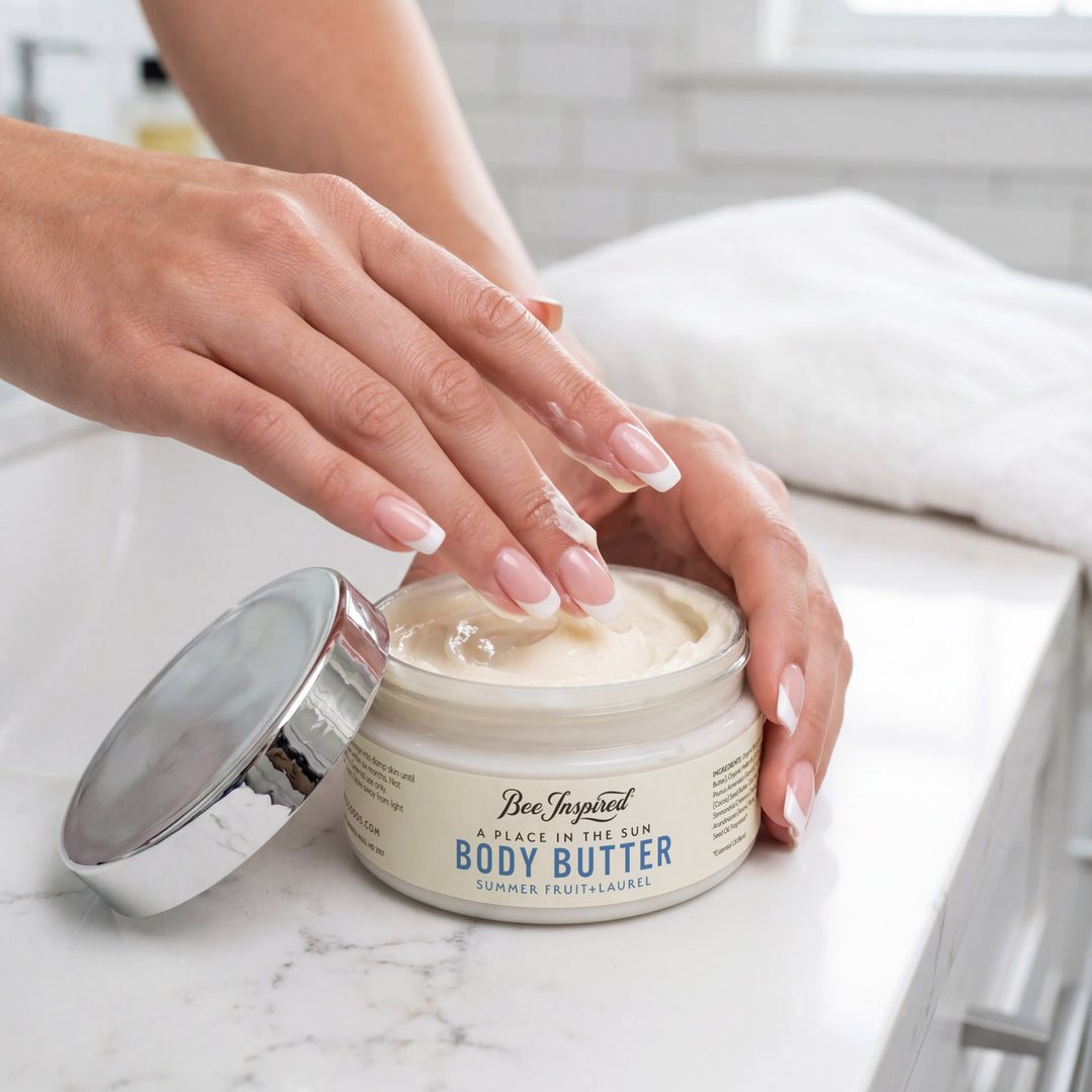 Person applying body butter from a jar on a marble surface