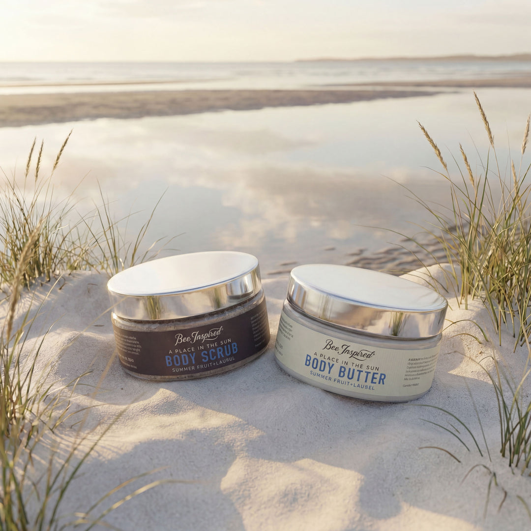 Two jars of Ben Elijah's Body Scrub and Body Butter on a sandy beach with grasses.
