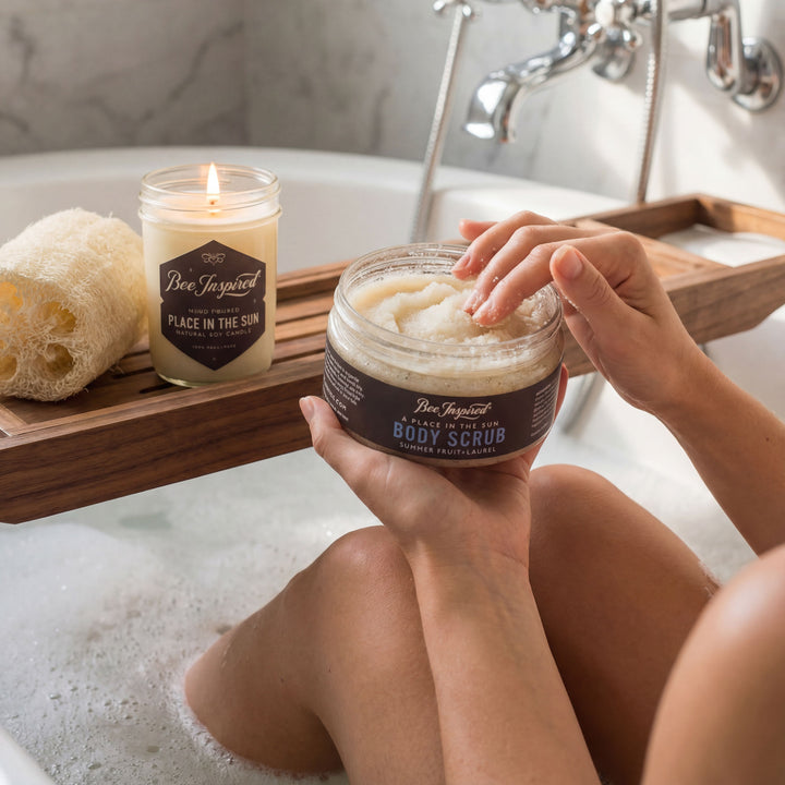 Person holding a jar of body scrub with a candle and loofah in the background