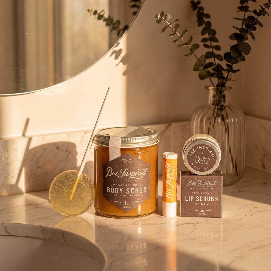 Bee Inspired body scrub, lip scrub, and other products on a bathroom counter with a mirror and plant in the background.