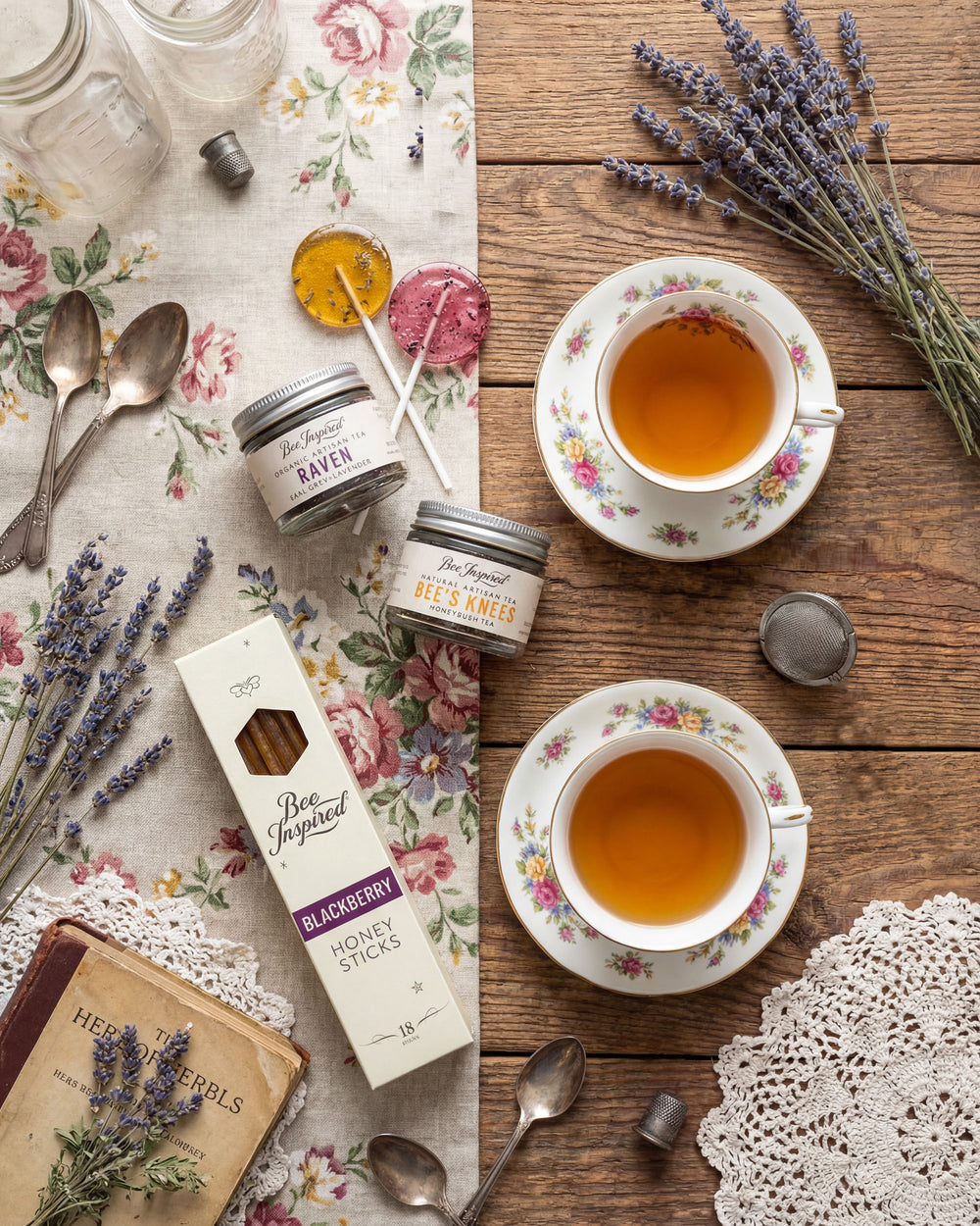 Tea cups, honey sticks, and lavender on a wooden table with floral patterns.
