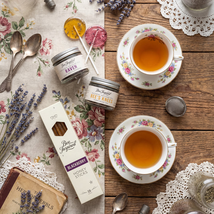 Tea cups, honey sticks, and lavender on a wooden table with floral patterns.