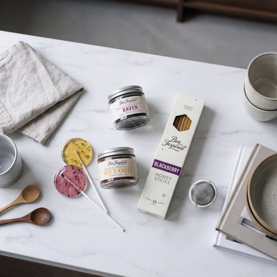 Tabletop scene with Bee & Raven products including jars, a box, and honey sticks on a marble surface.