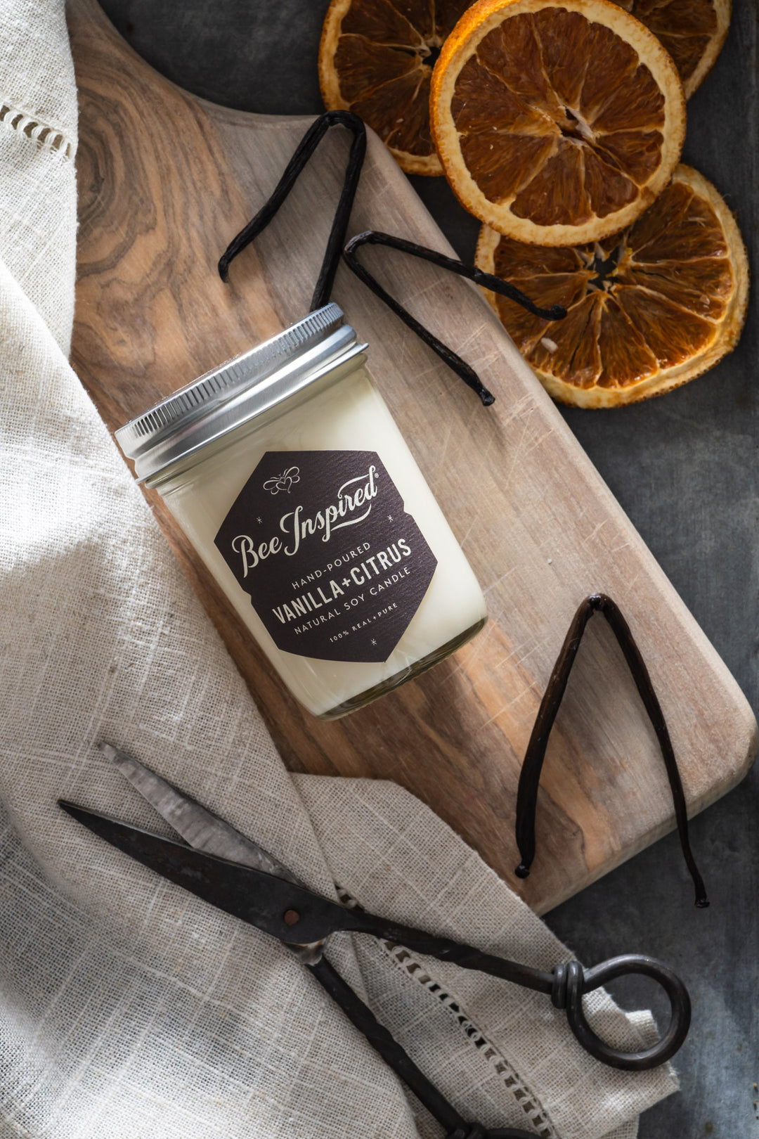 Vanilla Citrus jelly jar candle flat lay next to vanilla bean and dried oranges 