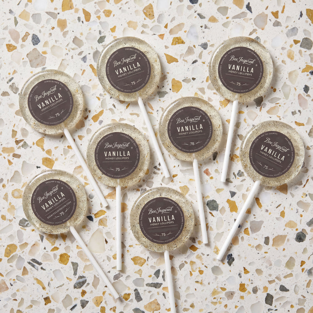 Vanilla lollipops with decorative paper labels on a terrazzo patterned surface