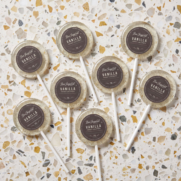 Vanilla lollipops with decorative paper labels on a terrazzo patterned surface