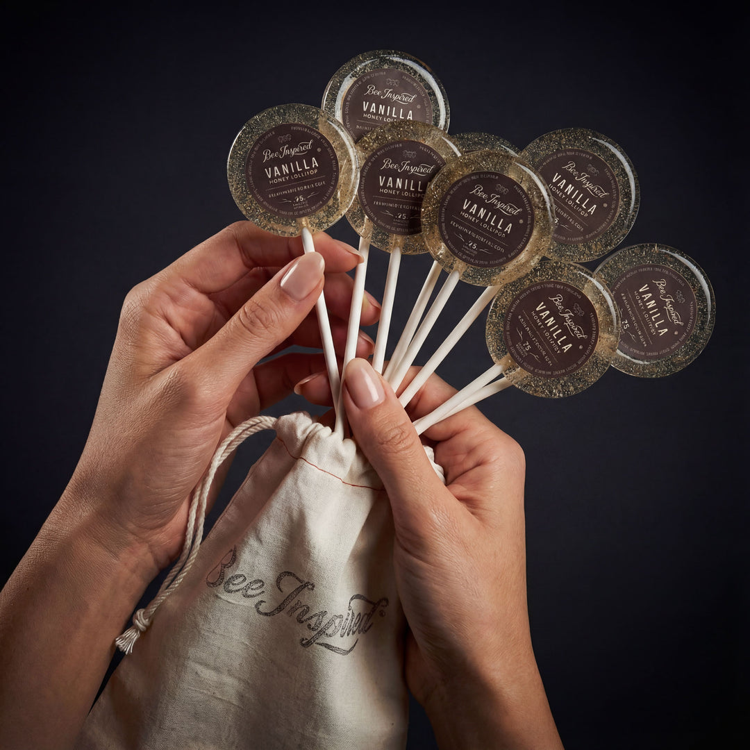 Hands holding vanilla extract pods above a drawstring bag with 'bee & spark' branding on a dark background.