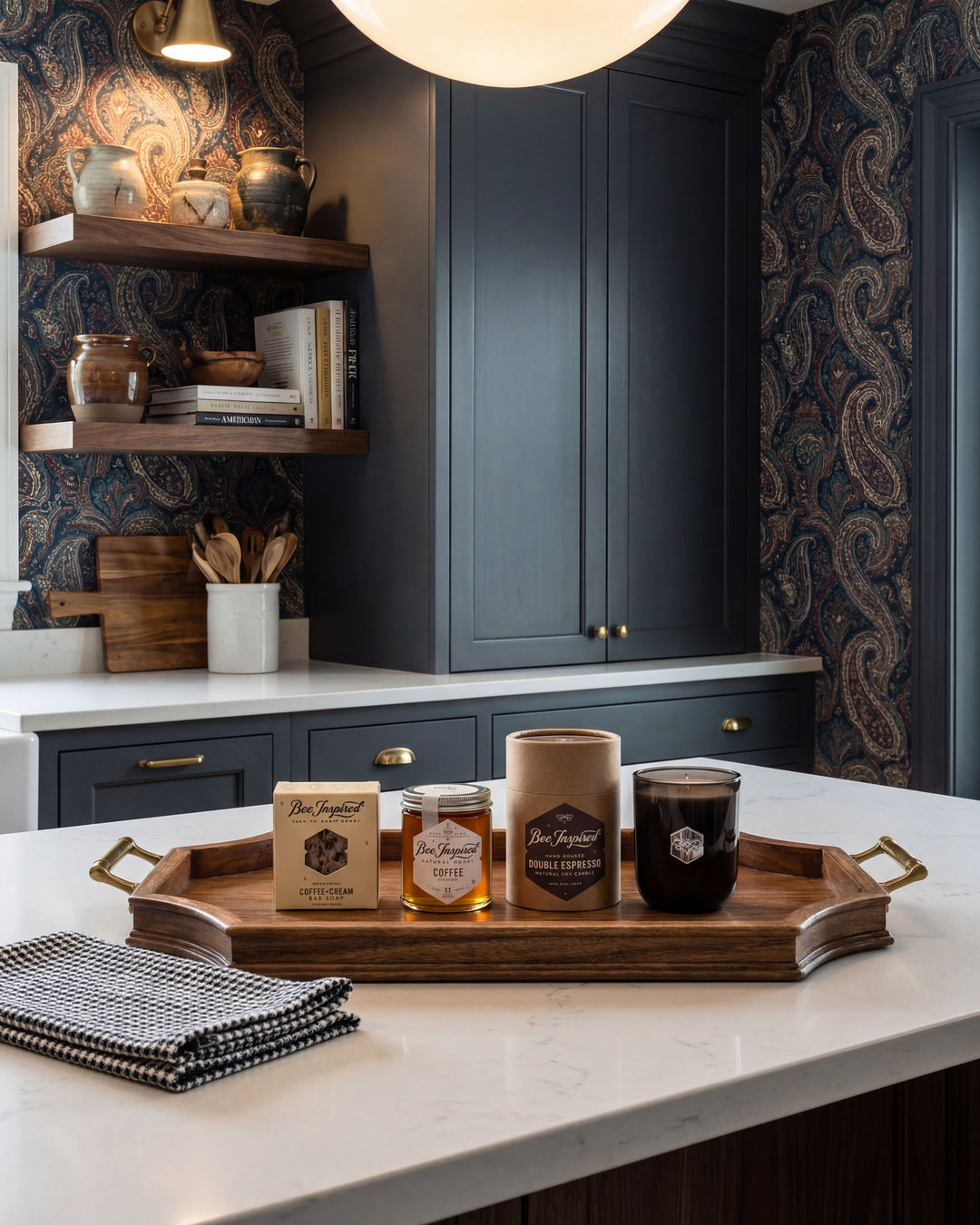 Café items including coffee cups and jars on a tray in a kitchen setting with dark blue cabinets and patterned wallpaper.