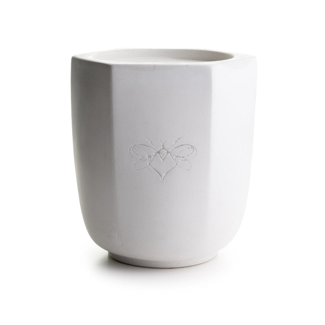A hexagonal candle with the Waxing Kara bee logo engraved on the side.